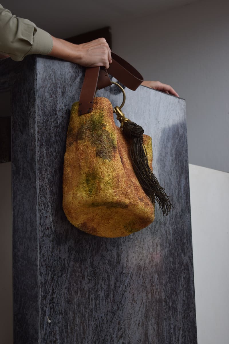 Persona alzando una mochila wayuu en un muro